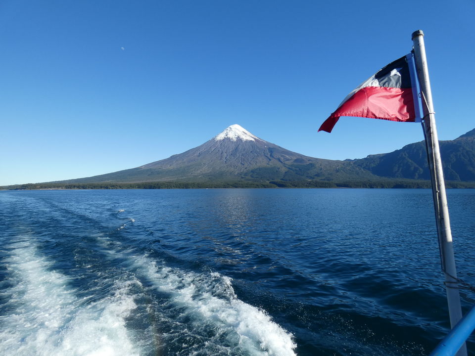 De Chileense vlag wappert aan boord van de Cruce Andino. Op de achtergrond de Osorno vulkaan, Chili