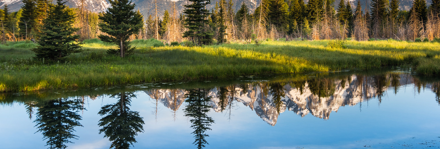 De wit besneeuwde bergtoppen weerspiegelen in het water in Grand Teton, Amerika © Wyoming Office of Tourism