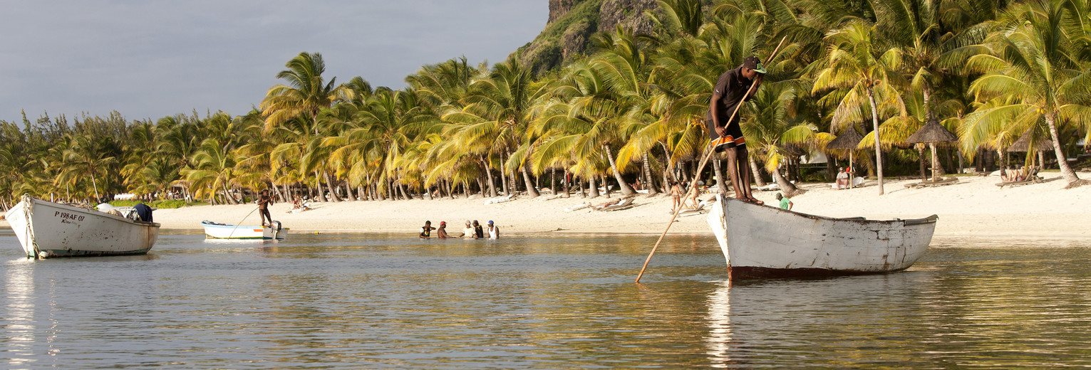 Een visser aan het werk vlak langs het zandstrand van Pointe aux Canonniers, Mauritius