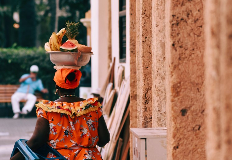 Een local wandelt met fruit op haar hoofd over de pleinen van Cartagena, Colombia