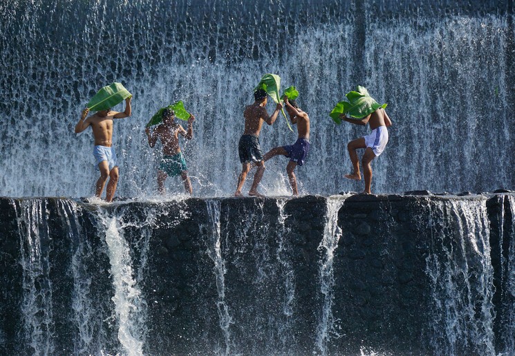 Spelende kinderen onder een waterval op Bali, Indonesië