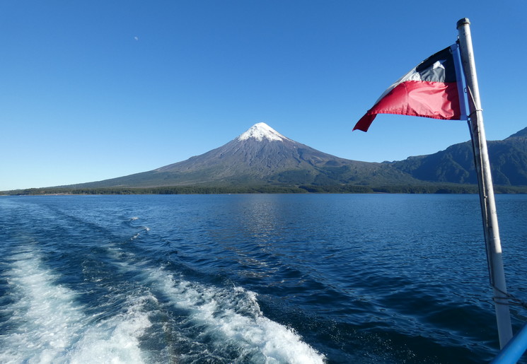 De Chileense vlag wappert aan boord van de Cruce Andino. Op de achtergrond de Osorno vulkaan, Chili