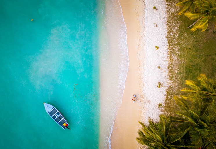 Wit zandstrand en azuurblauwe, turkooizen zee, kleine lokale boot in lagune van Mauritius