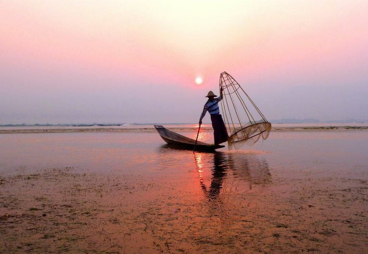 Lokale visser bij zonsondergang op Inle Lake, Myanmar