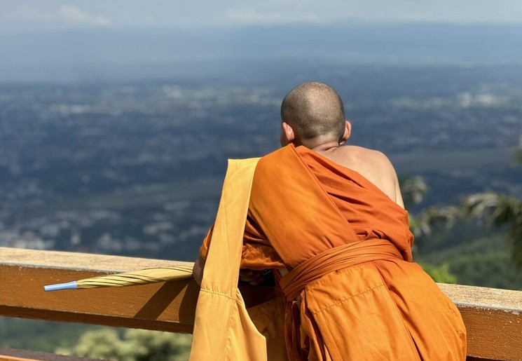 Een monnikkijkt uit over Chiang Mai vanuit de tempel