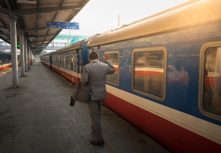 Zwaaiende man bij vertrekken treinstation Hanoi, Vietnam