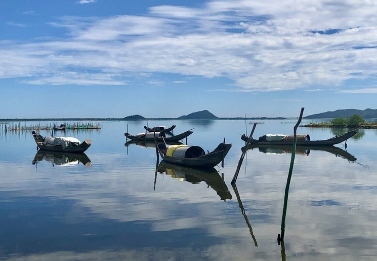 Onderweg van Hue naar Hoi An liggen er boten in de grote rivier