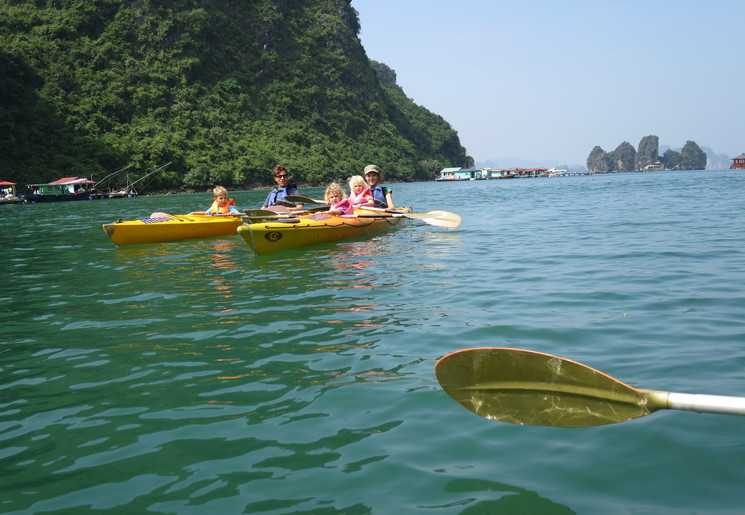 Een familie met kinderen peddelend in een kajak door de Halong Bay