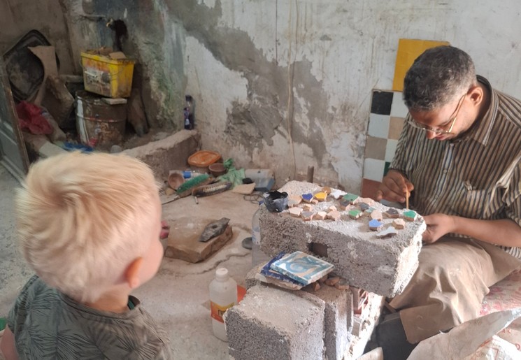Kindje kijkt rond bij het maken van de mozaieken in Marrakech