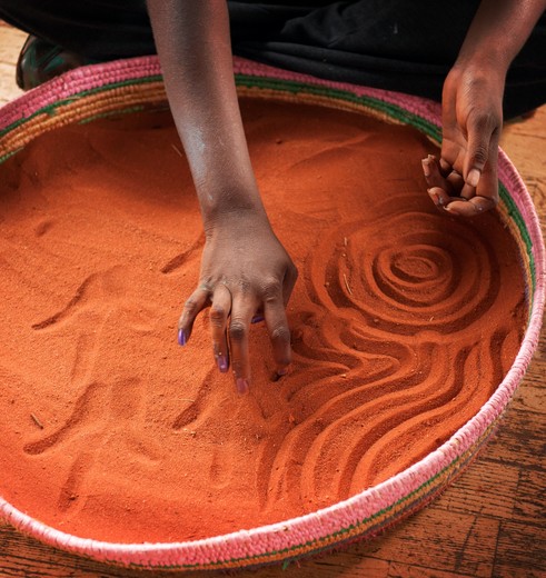 Een aboriginal maakt prachtige zandtekeningen in de omgeving van Uluru, Australië