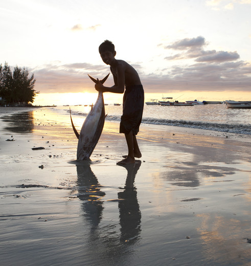 Een kind laat vol trots zijn vangst van de dag zien in de omgeving van Pointe aux Canonniers, Mauritius
