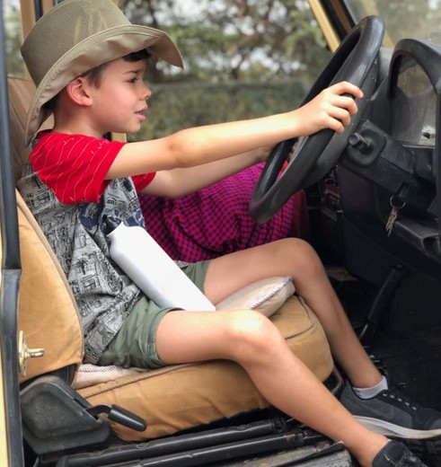 En klein jongetje achter het stuur van de safarijeep in Tanzania