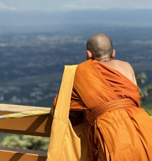 Een monnikkijkt uit over Chiang Mai vanuit de tempel