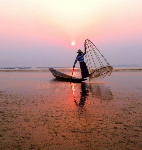 Lokale visser bij zonsondergang op Inle Lake, Myanmar
