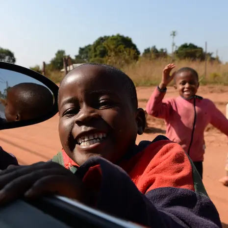 Nieuwsgierige kindjes klimmen in de auto in de omgeving van Mlilwane, Swaziland